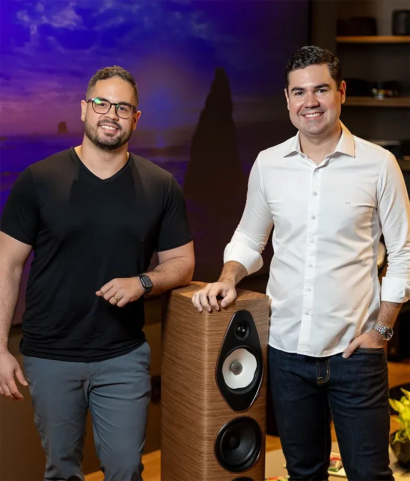 André e Bruno, fundadores da UNIUM, ao lado de uma caixa acústica